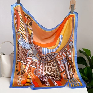 Detailed view of square silk scarf with horse and leopard print in orange and blue tones