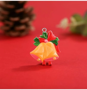 Detail of Christmas resin orange bell pendant with red bow and green leaves on red background