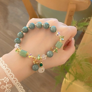 Detail of light green jade bead bracelet with golden spacers and a small jade pendant