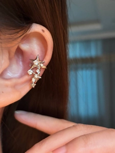 Detailed close-up of a silver-colored star ear cuff clip with sparkling crystal stones
