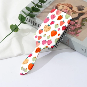Détail d'une brosse à cheveux à coussin d'air avec motif fraise et décor blanc