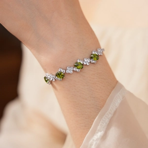Macro shot of silver zircon bracelet with green oval stones on a female wrist