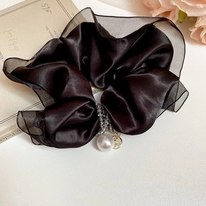 Close-up of black satin and organza scrunchie with elegant pearl and rhinestone charms