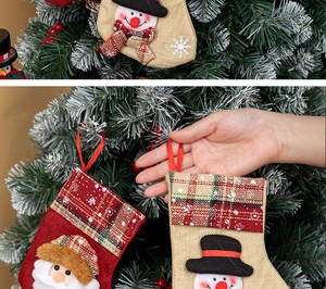 Close-up of rustic Christmas stocking hanging on a tree with Santa and Snowman designs