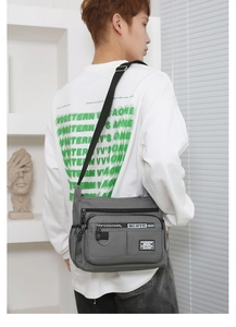 Man wearing dark grey multi-pocket nylon crossbody bag showing its large capacity and style