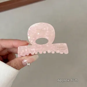 Close-up of pink marble acetate hair claw clip with golden Barrette la France text
