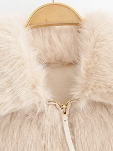Detailed view of plush faux fur collar and premium gold zipper on beige jacket