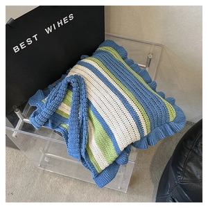 Detail showing blue and green striped knit tote bag with elegant ruffled wavy edges
