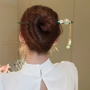 Detail of wooden hair stick with green jade-like ring and delicate floral tassel