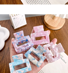 Close-up of five acetate marble textured square hair claws in a modern lifestyle setting