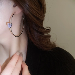 Gros plan d'un mannequin portant des boucles d'oreilles C en cœur avec zircon violet poli
