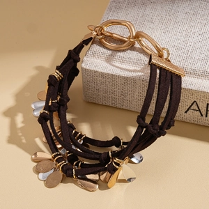 Détail du bracelet multicouche en daim marron avec pendentifs métalliques dorés et argentés