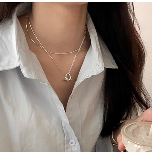 Dettaglio della collana a doppio strato argento con chiusura OT sul collo di una modella