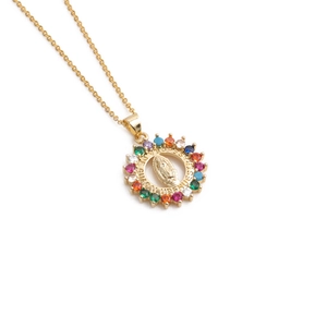 Macro detail of oval gold pendant with cubic zirconia and Guadalupe engraving
