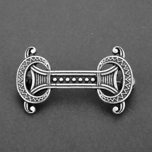 Detailed macro view of vintage silver alloy brooch with Nordic relief and scrollwork patterns