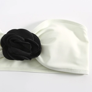 Detail of a white bandeau bikini featuring a large handcrafted 3D black fabric rose