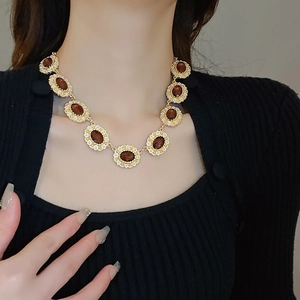 Detail of vintage gold necklace with oval brown gems and crystals on a model