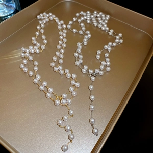 Gros plan de colliers en Y superposés en or et argent avec perles d'imitation