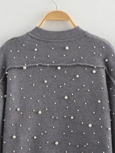 Close-up of a grey knitted jacket featuring elegant pearl beads and ribbed collar detailing