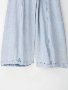 Detailopname van de lichtblauwe denim textuur en de dubbel gestikte zoomlijn