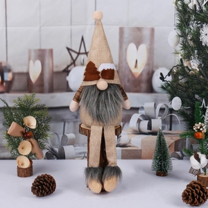 Sitting Christmas gnome doll with long legs and grey beard on wood stump for holiday decor