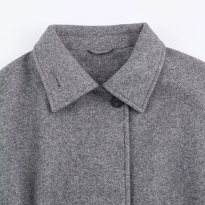 Detailed view of grey wool coat featuring notched lapels and premium fabric texture