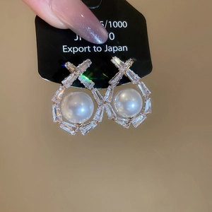 Detailed macro view of geometric hollow earrings with inlaid pearls and baguette zircons
