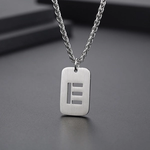 Macro d'un pendentif rectangulaire argenté avec découpes sur une chaîne en métal brossé