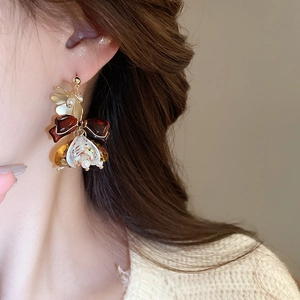 Gros plan de boucles d'oreilles asymétriques avec nœuds rouge foncé et pendentifs colorés