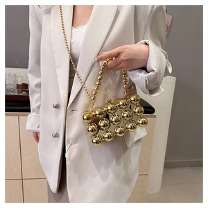 Detail of a chic gold beaded acrylic box clutch bag with elegant chain strap on a white blazer