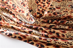 Close-up of leopard print satin scarf showing silky texture and glossy animal pattern