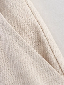 Close-up of beige cotton linen fabric texture and flat stitched seam on the garment