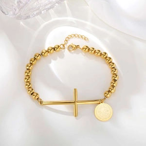 Detail of golden stainless steel beaded bracelet featuring cross and oval religious medal