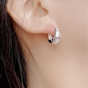 Macro shot of silver S925 sterling silver hoop earrings with star engraving on earlobe