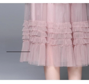 Détail de la jupe en tulle rose clair multicouche avec volants et dentelle
