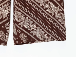 Detail of coffee brown cotton fabric with white paisley print for vacation set