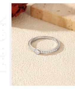 Macro shot of silver ring with round moissanite and pave stones on textured surface