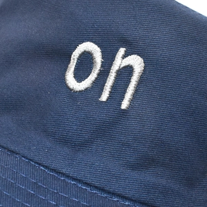 Detail of white oh embroidery on navy cotton twill sun hat with fine stitching
