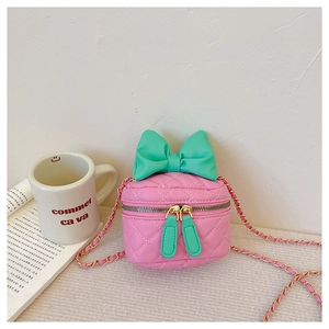 Detail of pink quilted kids crossbody bag with green bow and gold chain strap
