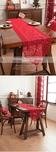 Macro shot of festive red lace Christmas table runner with hollow embroidery and tassels