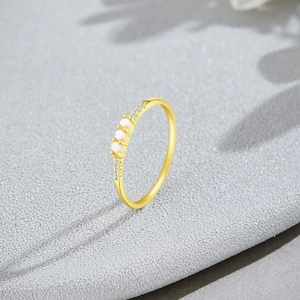 Macro shot of gold ring showing three round white gems and tiny side zircon accents