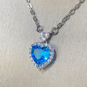 Detailed view of silver heart pendant with blue topaz gemstone and sparkling pavé halo