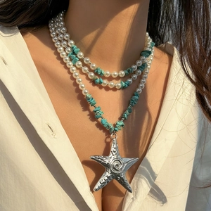 Detail of layered pearl and turquoise stone necklace with large starfish pendant