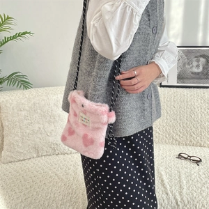 Gros plan du sac bandoulière en peluche rose à cœurs sur mannequin montrant la texture