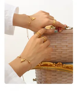 Close-up of a gold heart pendant bracelet and stacked rings on a hand in vintage setting