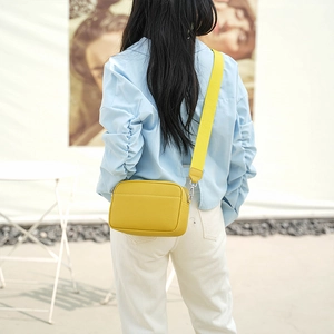 Detail view of yellow lychee grain PU leather crossbody camera bag with wide fabric strap