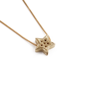 Macro detail of gold-plated star pendant with hollow star patterns on a gold chain