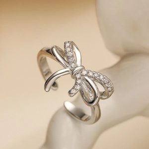 Detailed view of silver bow ring featuring micro-paved zircons on minimalist stand