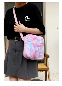Detail of pink and blue tie-dye crossbody bag with star print and woven strap