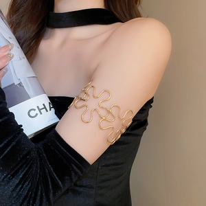 Detailed view of an adjustable golden hollow wave floral pattern arm cuff on a model